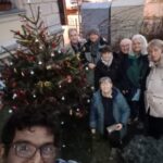 Truppe von ehrenamtlichen Helfern mit fertig geschmücktem Tannenbaum